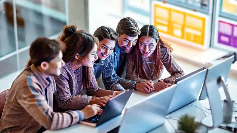 Estudiantes colaboran digitalmente en un espacio moderno